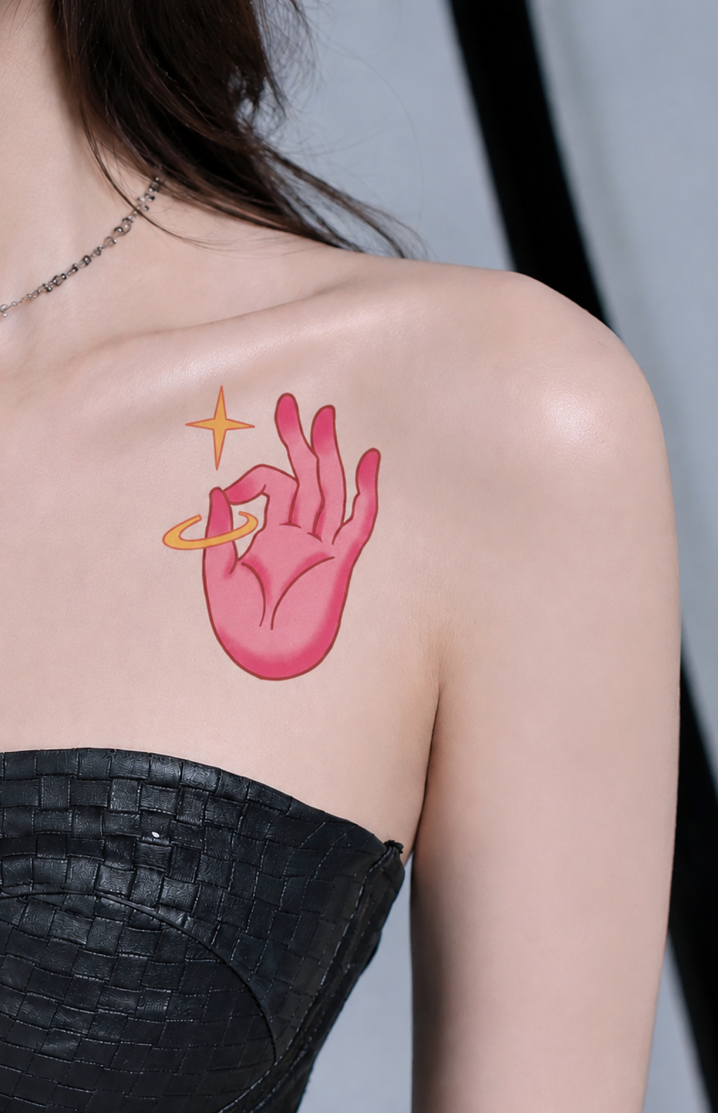 Pink illustrated hand tattoo placed below shoulder